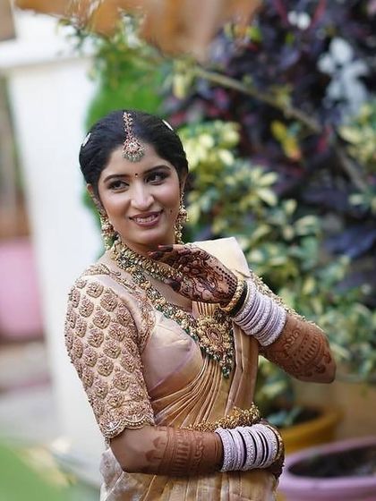 A happy bride posing in a garden, her smile as bright as her beautiful mehendi.