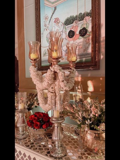 A console table styled with a candelabra draped in 'gajra' (jasmine garlands) and a bowl of red roses. The fragrance and visual appeal created a truly traditional and opulent feel.