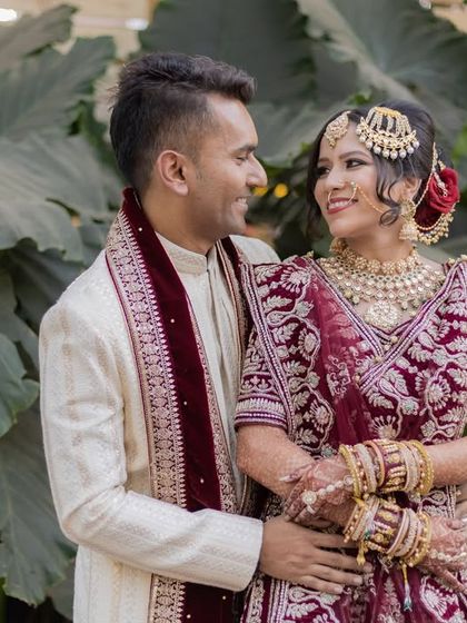 A classic romantic portrait of the couple looking at each other, set against a natural green backdrop.