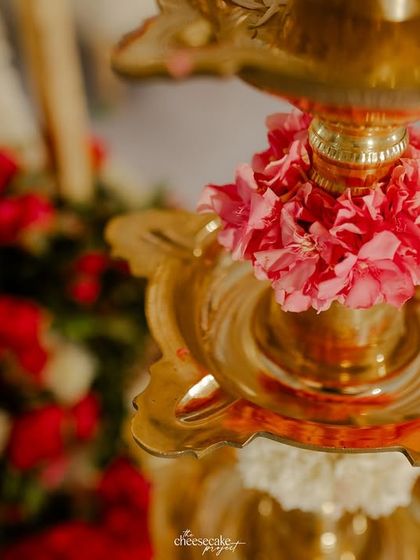 A close-up of a traditional brass 'diya' (lamp) decorated with fresh flowers.