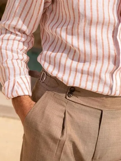 A striped linen shirt paired with pleated trousers featuring side adjusters. This is a classic, elegant combination for any smart-casual summer occasion.
