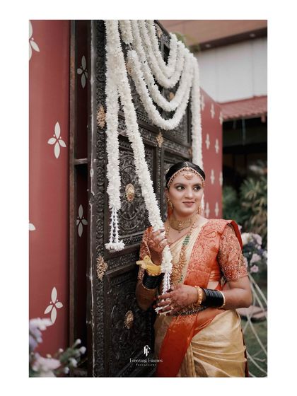 A bride holding a long garland of jasmine flowers, a beautiful and traditional element of South Indian weddings.