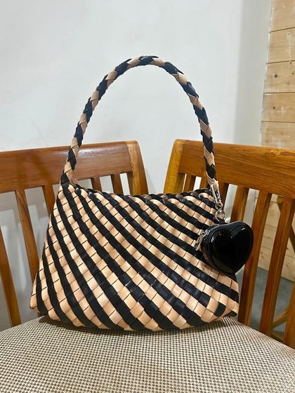 A fun bag for work, the handwoven Gaia in a striking black and natural stripe pattern. Crafted from vegetable-tanned leather, its trapezium shape makes a statement.