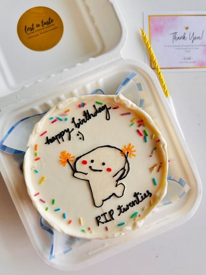 A humorous take on a milestone birthday. This "RIP twenties" bento cake features a cheerful character and colorful sprinkles to celebrate entering a new decade.