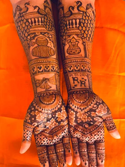 A personalized bridal mehendi featuring the couple's initials, the wedding date, and traditional motifs like peacocks and dhol drums.