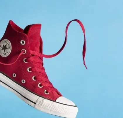 A vibrant, dynamic shot of a red high-top sneaker suspended against a solid blue background. This style of creative product photography grabs attention and is ideal for social media and ad campaigns.