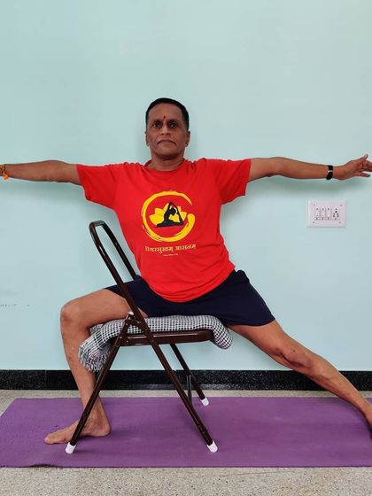 Veerabhadrasana 2 (Warrior 2) practiced on a chair. This variation is excellent for understanding the rotation of the torso and the alignment of the arms and legs while supporting the hips.