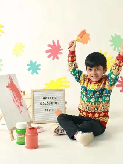 Pure creative joy! He raises his paintbrush in triumph during his colorful artist-themed fifth birthday shoot.