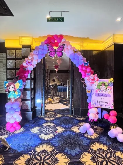 An entrance arch for a fairy-themed birthday party. We created a welcoming balloon arch in pink and purple over the doorway, complete with a large butterfly cutout and a welcome board for guests.