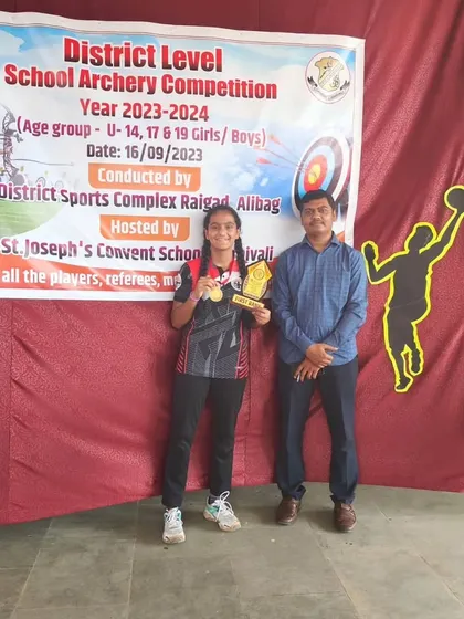 Celebrating another gold medal winner at the District Level School Archery Competition. She is holding her medal and trophy, representing her hard-earned victory.