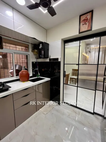 A view of the kitchen showing the fluted glass partition that connects to the dining area. This design allows for an open feel while still defining the kitchen space. You can also see the portrait of Babaji, a personal touch for the client.