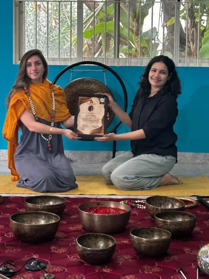 A student receives her Sound Healing certificate in front of a large gong, one of the powerful instruments used in our training.