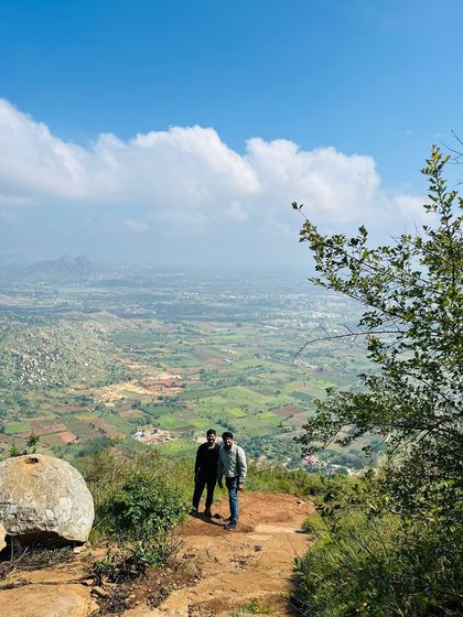 Two trekkers posing against a vast, green landscape.