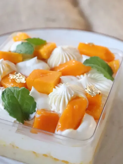 A close-up of the Mango Tres Leches Tub, highlighting the fresh mint, mango chunks, and gold leaf.