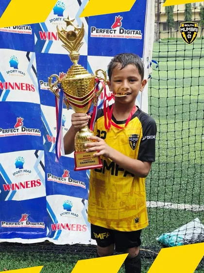 Biting the medal, a classic champion's pose. Our U8 player celebrating a well-deserved win after a tough tournament.