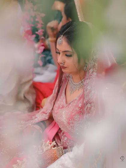An artistic shot of the bride during the ceremony, framed by foreground elements to create a sense of depth and intimacy.