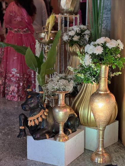 A close-up of a traditional decor corner, featuring a Nandi statue, brass vases, and fresh white flowers, creating a serene and sacred ambiance.