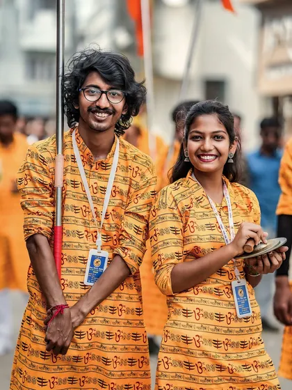 A happy portrait of two members of the troupe, a flag bearer and a cymbal player, sharing a smile during the procession.