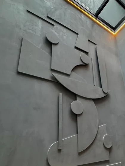 A custom-designed mural serves as the central art piece in this home. Crafted from microconcrete, the geometric shapes create a dynamic play of light and shadow, especially when illuminated by the skylight above.
