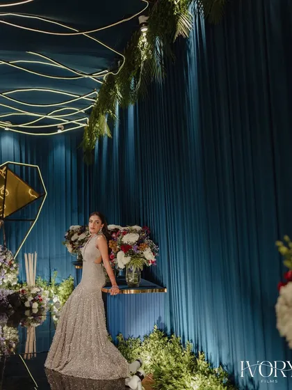 Another perspective of the bride against the stunning Sangeet decor, showcasing the scale of the floral arrangements and the unique lighting design.