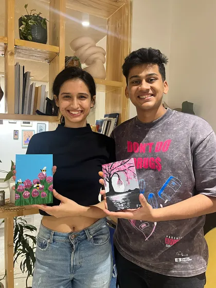 A young couple with their charming small-scale paintings, one of bees on flowers and the other a moody landscape.