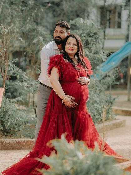 A sweet embrace captured during an outdoor shoot. The mom-to-be looks radiant in the ruffled red ball gown, perfect for celebrating this special time with a partner.