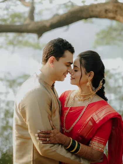 An intimate portrait by the water. The couple's closeness and the soft, natural lighting create a romantic and serene atmosphere, highlighting the elegance of their traditional Maharashtrian wedding attire.