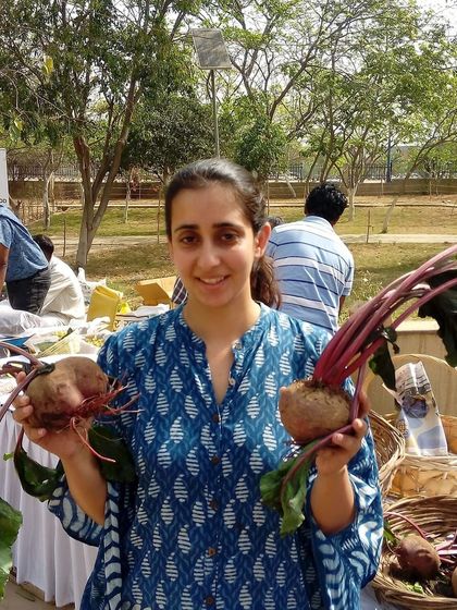 A smiling customer holding up two large, fresh beetroots.