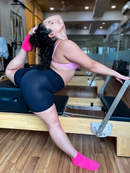 True flexibility is a hallmark of a uniformly developed body. This beautiful pose on the Reformer highlights the incredible range of motion and muscular control that you can achieve through our Pilates programs.