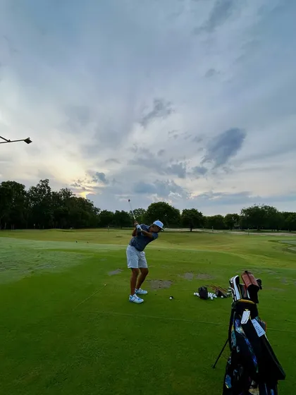 A beautiful shot of a golfer's follow-through against a dramatic, cloudy sky.