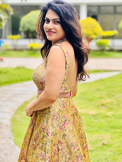 Amulya smiling in her floral brocade gown, a perfect fusion of traditional fabric and a modern, backless silhouette.