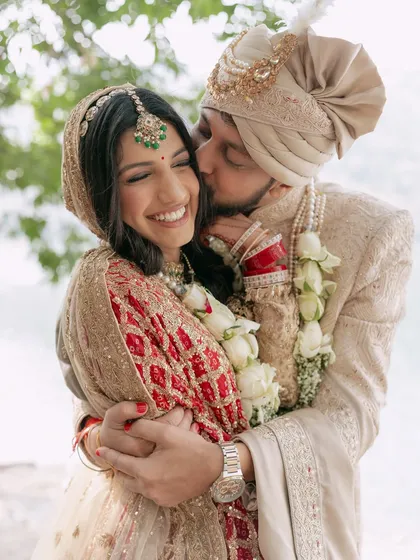 A moment of pure, unscripted joy during a lakeside wedding in the hills. The groom's happy kiss on the bride's cheek says it all.