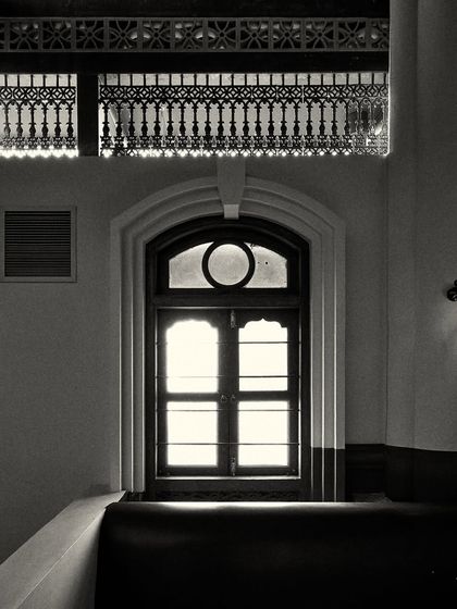A similar arched window, framed by intricate decorative molding above. These details add to the historical, Calcutta-inspired theme.