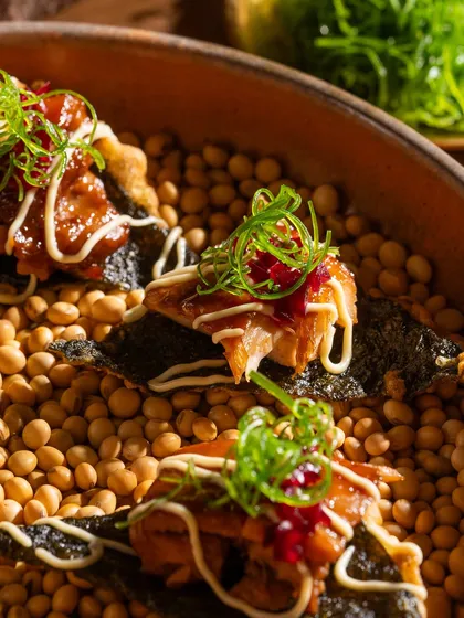 A macro shot of the teriyaki chicken bites, showing the detail of the glaze, sauce, and garnish.