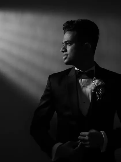 A striking black and white portrait of a groom in his tuxedo. The dramatic shaft of light adds a cinematic and sophisticated feel to this classic getting-ready shot.