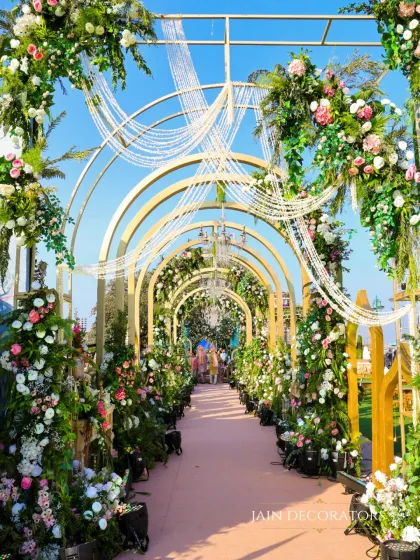 A fairytale entrance for a daytime wedding. Golden arches are adorned with lush florals and hanging crystal strings, creating a beautiful play of light and color as guests walk through.