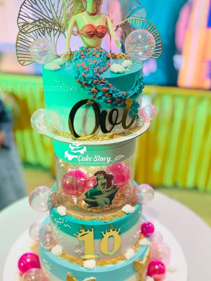 A spectacular mermaid-themed rotating cake for a 10th birthday. This multi-tier creation features a mermaid doll, under-the-sea details, and a rotating center with bubble effects.