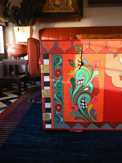 This view from the side highlights the intricate floral scrollwork, a hallmark of Kalamkari art. The play of light on the painted surface reveals the depth and texture of the artwork.