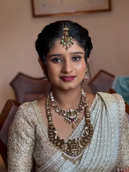 A close-up of Ramya, the sister of the bride. Her makeup is fresh and youthful, with a focus on glowing skin and a pretty berry lip.