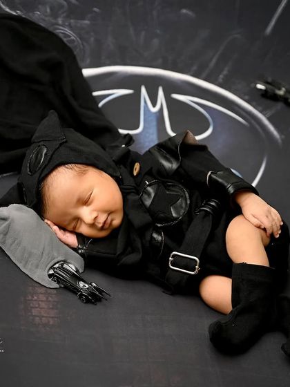 The hero Gotham deserves. This newborn is dressed as Batman, complete with a cape and Batmobile, ready to protect the city in his dreams.