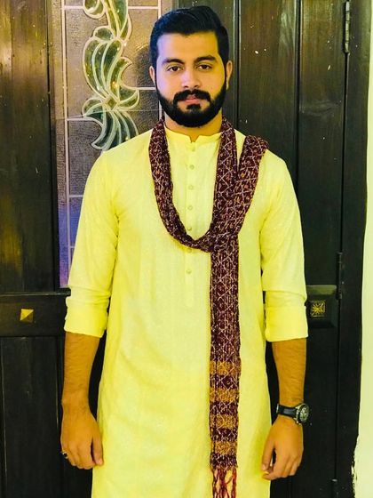 A simple and elegant Haldi look. The groom wears a yellow kurta with a printed scarf, looking comfortable and stylish.