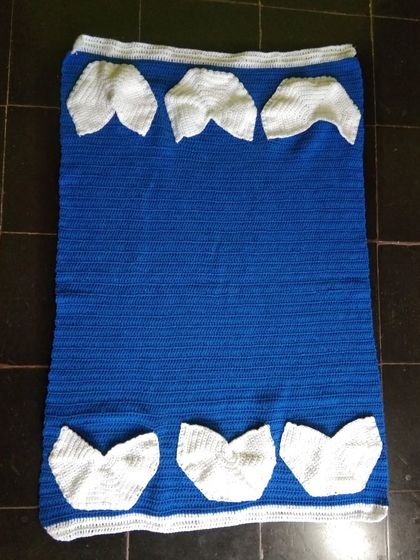 A custom crochet fridge cover in blue and white with handy pockets.