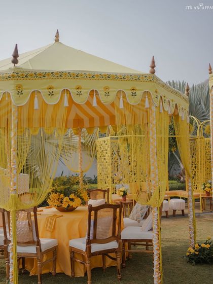 An elegant yellow tented cabana provides a shaded and stylish dining area for guests.