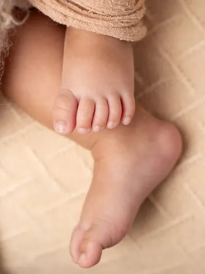 A macro shot of a newborn's foot, nestled in soft, warm blankets. I use special lenses to capture these details with stunning clarity.