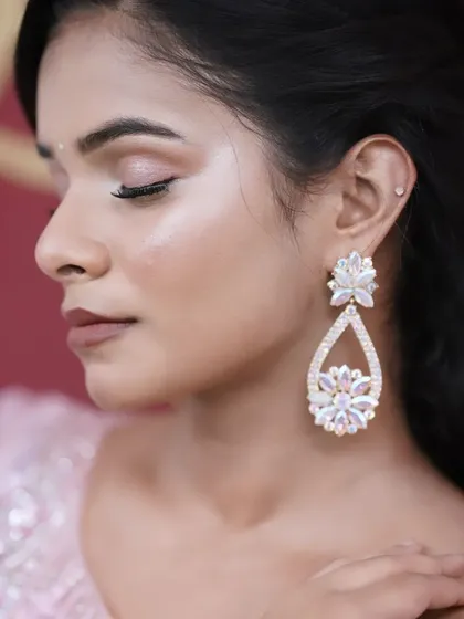 A side profile showing off the stunning statement earrings and the subtle shimmer of the highlighter on the cheekbones.