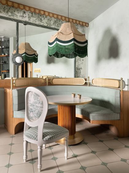 A custom-upholstered chair with a classic silhouette sits beside a curved booth. The mix of gingham and floral-patterned fabrics demonstrates our approach to layering patterns in a subtle, sophisticated way.