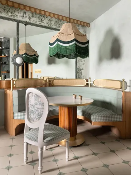 The custom seating at 11 Grams Cafe includes this classic chair with a carved white frame, upholstered in a mix of toile and gingham fabrics, perfectly capturing the cafe's romantic, old-world charm.