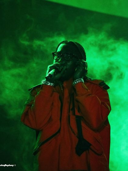 Don Toliver in his orange jacket, surrounded by green smoke. This shot is a great example of using complementary colors in concert photography.