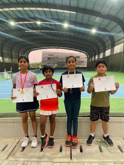 Four young participants from a UTR event proudly display their certificates and medals. We encourage participation at all levels to build a strong foundation for competitive tennis.