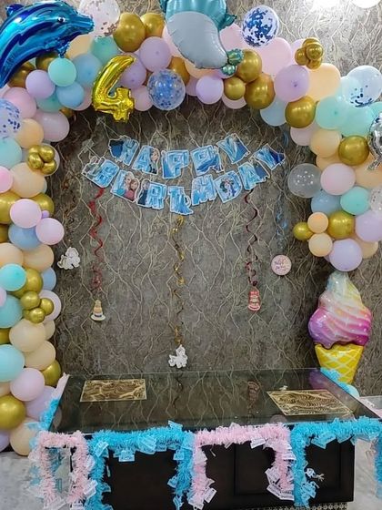 An under-the-sea themed party for a 4th birthday. The balloon arch includes dolphin and ice cream cone foils for a fun, whimsical touch.